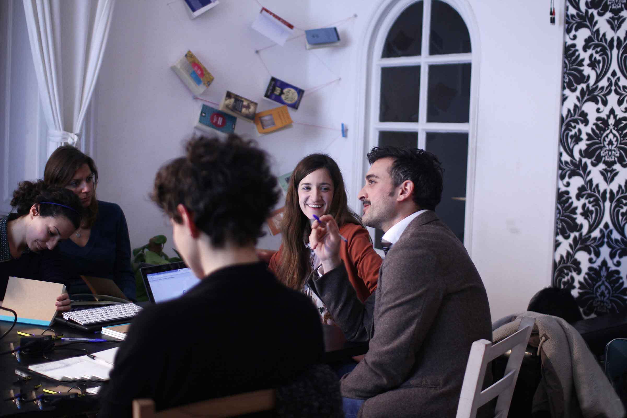 People around a table during a workshop, an arched window behind them