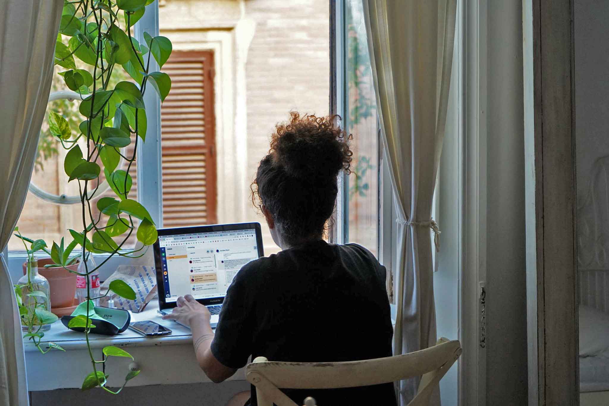 A resident working on a laptop at an open window